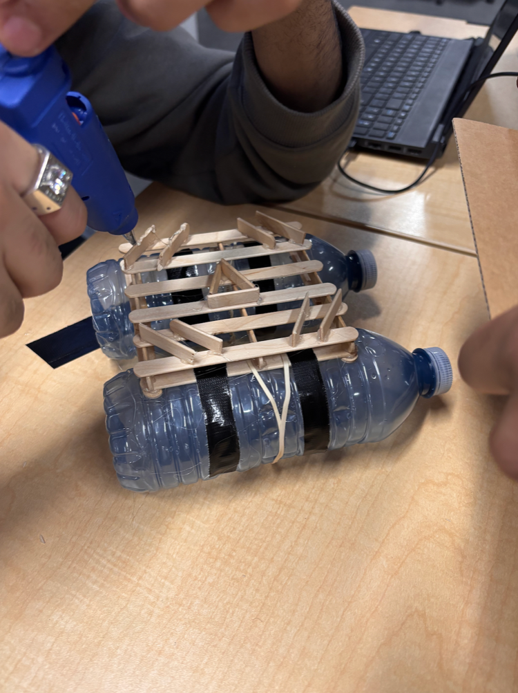 Buoy prototype being assembled with popsicle sticks and bottles.